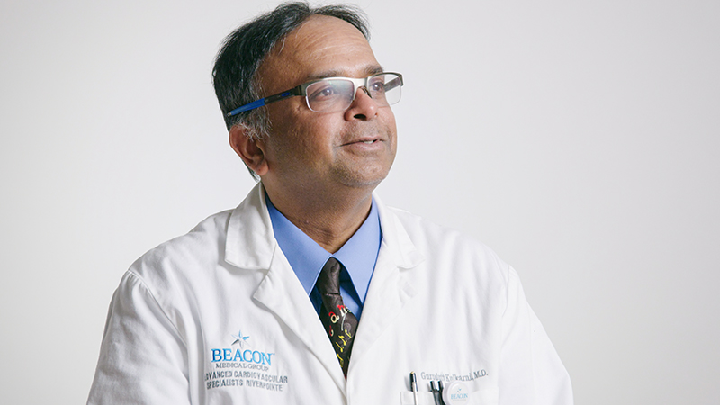 Male provider wearing lab coat and glasses, smiling