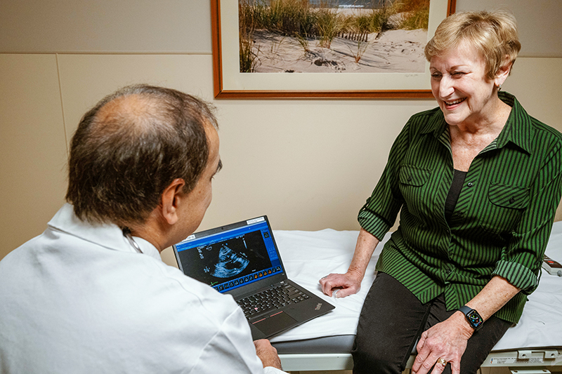 Smiling female patient in medical office talks to male provider as they review a computer scan