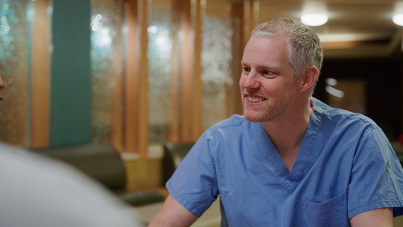 Provider in blue scrubs, smile and facing a person