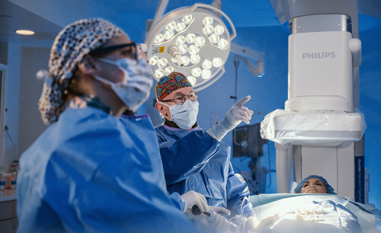 male and female provider in operating room with patient lying on a table